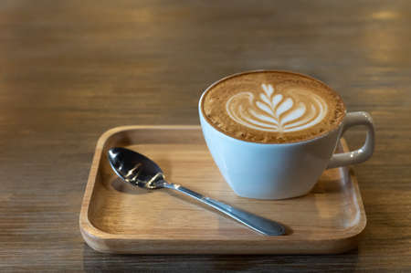 Latte art coffee cup with spoons on plateの写真素材