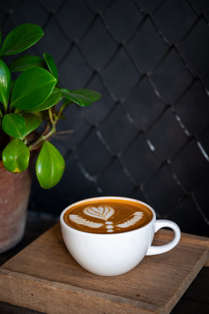 Latte art coffee cup on wooden plate in dark background.の写真素材