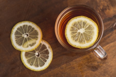 Top view of black tea with lemon in cup and on wooden plank table.の写真素材