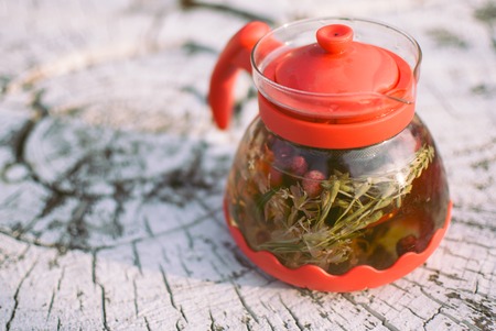 teapot of fruit tea with herbs and berry on the white tree stump.の写真素材