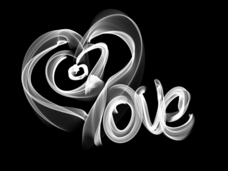 Love isolated word lettering and heart written with fire flame or smoke on black background.の写真素材