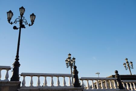 lamp posts on a pier with railing at sunny spring day with clear blue skyの写真素材