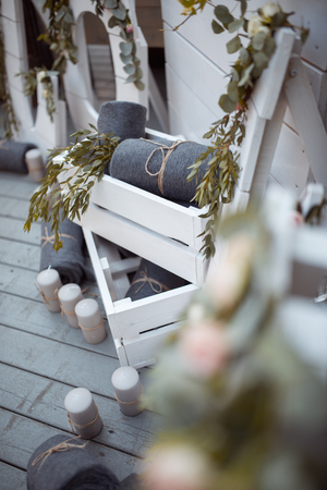 A lot of white painted wooden cage boxes, some with decorative candles, rolled blankets and domestic plantsの写真素材