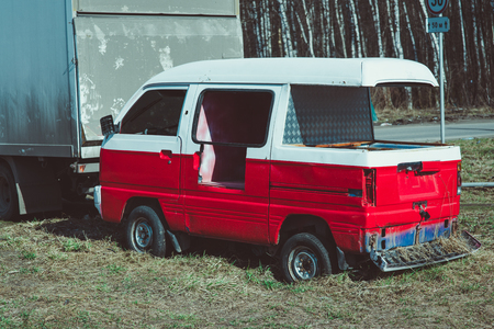 Old rusty, abandoned red and white bus wreck in arid Forest landscape with birchesの写真素材