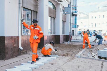 Moscow, Russia - August 14, 2015: builderworkers laid a new tile on the Pavement. Reconstruction of pavement tiles in the capital near palace Chertkov House. Myasnitskaya streetのeditorial素材