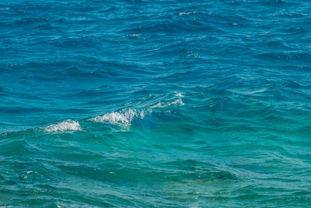 Wide shot of a beautiful clear turquoise sea ocean water surface with low ripples and subtle waves...