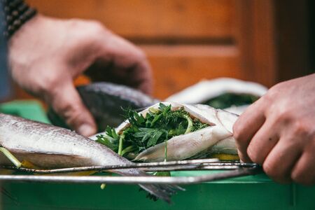 the man stuffed fresh and raw fish. With lemon and parsley on a barbeque grill in the garden in summer, ready and wait for the rost. Selective focus macro shot with shallow DOFの写真素材