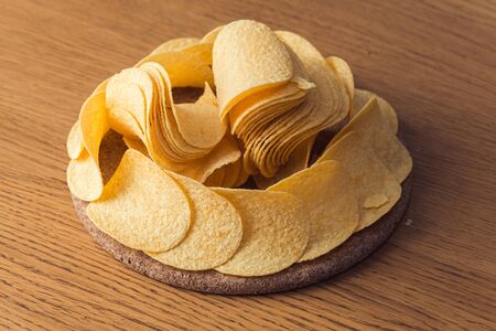 Delicious potato chips, laying on wooden table background
