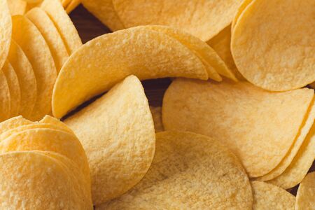 Delicious potato chips, laying on wooden table backgroundの写真素材