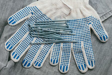 A handful of metallic self-cutters screws lies against the backdrop of an old denim fabric and construction gloves. Top Lay viewの写真素材