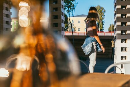 long-haired beautiful young blonde in a pink T-shirt, light blue jeans and tied at the hips denim...