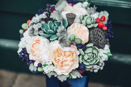 Handmade flowers made from Japanese polymer clay. They look like a real wedding bouquet. Against the background of a green wooden door.の写真素材