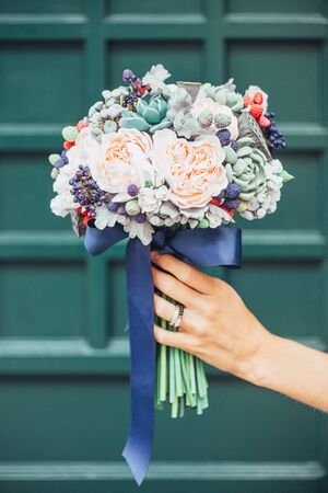 Handmade flowers made from Japanese polymer clay. They look like a real wedding bouquet. Against the background of a green wooden door.の写真素材