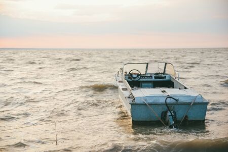 A lonely fishing motor boat in the sea against the background of the evening sunset sky.の写真素材