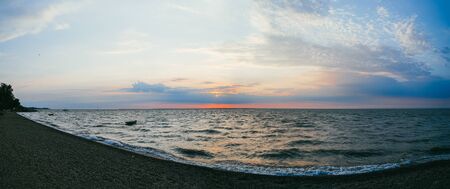 A lonely fishing boat in the sea against the background of the evening sunset sky. Large panoramaの写真素材
