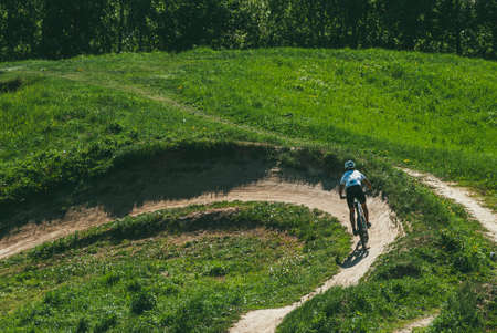 Moscow, Russia - may 21, 2014: Young woman with bicycle riding in the mountains. She wears a bicycle helmet and uniform. She makes a downhill descent downのeditorial素材
