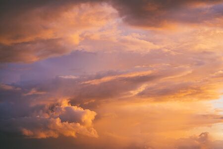 Evening sunset sky with bright rays of the sun and beautiful colorful clouds