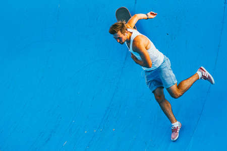 Moscow, Russia - AUGUST 9, 2014: young man jumped off a skate while doing sports on a ramp in Sokolniki park on a bright summer day. He wears adidas sneakersのeditorial素材