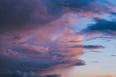 Evening sunset sky with bright rays of the sun and beautiful colorful clouds.