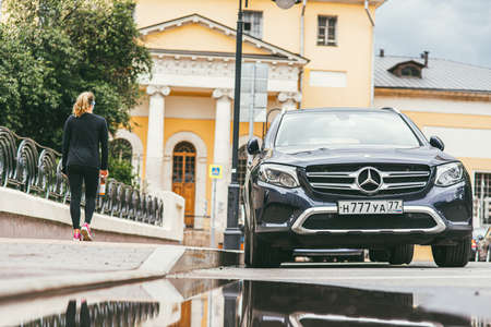 Moscow, Russia - JULY 7, 2017: A young girl with a sporty figure walks past a deep blue Mercedes Benz GLC 250 4Matic 2019のeditorial素材