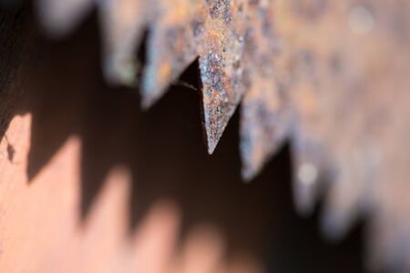 Teeth of a rusty old hand saw made on a macro lens. Close-up with a very blurry backgroundの写真素材