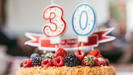 raspberries blackberry birthday cake with candles number 30 on defocused background. Selective focus macro shot with shallow DOFの写真素材