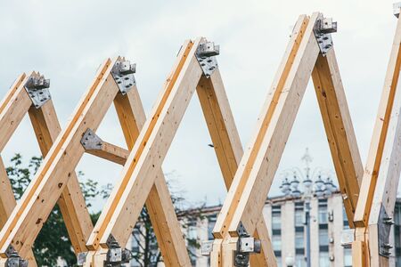 Wooden rafters of unfinished roof against the background of the city and white sky. The concept of building and creating new housingの写真素材