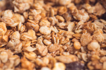 Useful and tasty muesli with nuts, rasins and flakes. Selective focus macro shot with very shallow depth of field. Healthy and vegetarian lifestyleの写真素材