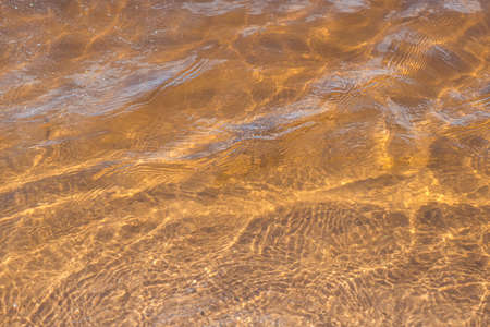 Golden sand of the beach under clear water of sea