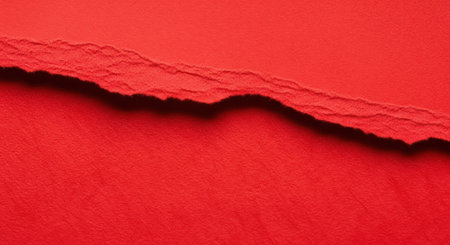 An abstract close-up captures a dynamic red surface with a rough, dark, jagged edge, creating a striking visual contrast and texture.の素材