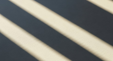 Abstract pattern of diagonal light and shadow stripes on a textured surface.の素材