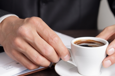 Businessman makes coffee break after work with diaryの写真素材