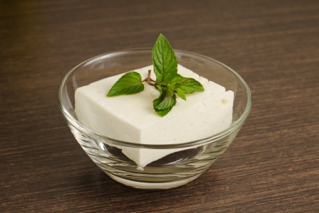 A piece of White Cheese in Glass Bowl on wooden backgroundの写真素材