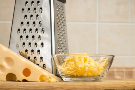 Grated cheese in Glass Bowl with Grater. Front viewの写真素材