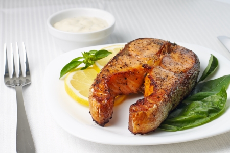 Salmon Steak with Lemon and Basil on white plateの写真素材
