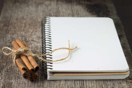 Blank Recipe book with bunch of cinnamon on old wood boardの写真素材