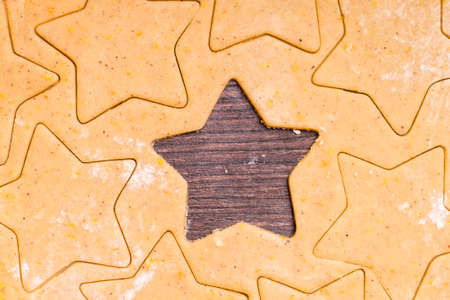 Gingerbread cookies dough with star shapes on wood backgroundの写真素材