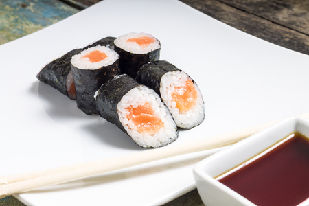 Makisushi on white plate. Seafood traditional maki sushi rolls with chopsticksの写真素材