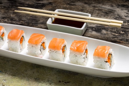 Seafood Sushi rolls in White Long Dish with soy sauce on old wooden tableの写真素材