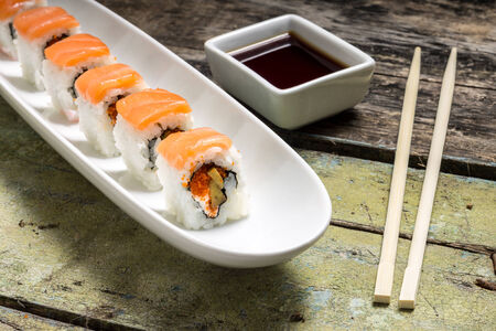 Seafood Sushi rolls in White Long Dish with soy sauce on old wooden tableの写真素材