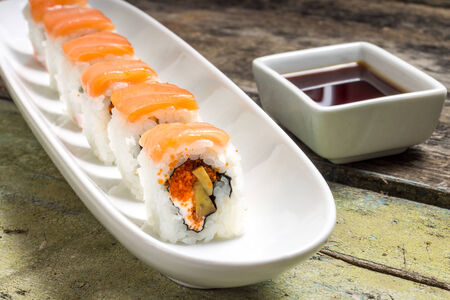 Seafood Sushi rolls in White Long Dish with soy sauce on old wooden tableの写真素材