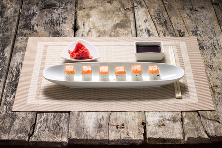 Seafood Sushi rolls in White Long Dish with soy sauce on old wooden tableの写真素材