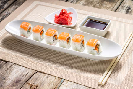 Seafood Sushi rolls in White Long Dish with soy sauce on old wooden tableの写真素材