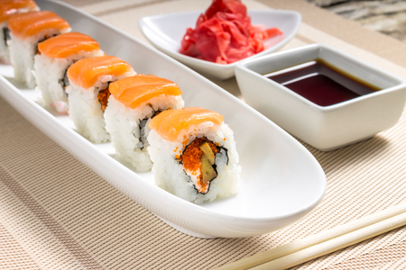 Seafood Sushi rolls in White Long Dish with soy sauce on old wooden tableの写真素材