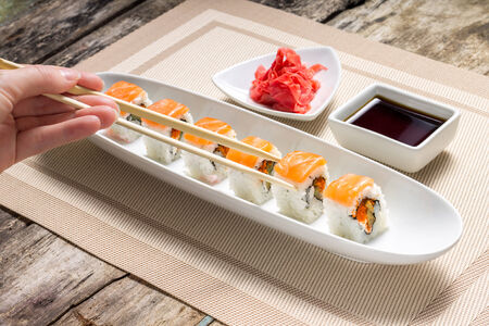 Eating with chopsticks seafood sushi rolls with traditional spicesの写真素材