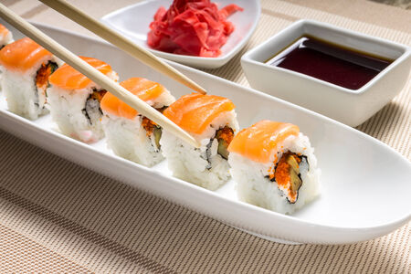 Eating with chopsticks seafood sushi rolls with traditional spicesの写真素材