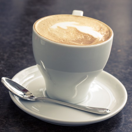 Cup of Cappuccino served in cafe. Warm color toned imageの写真素材