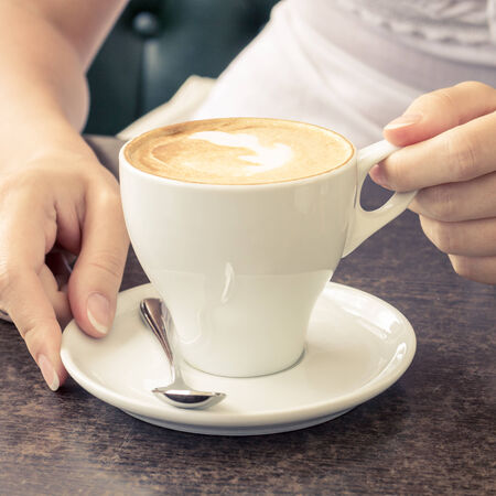 Morning coffee. Cup of Cappuccino in Cafe. Girl tasting creamの写真素材