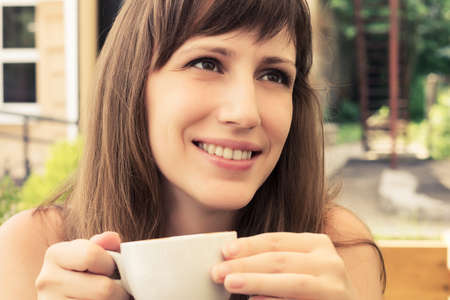 Portrait of young woman sitting in cafe. Dreaming girl with cup of coffeeの写真素材