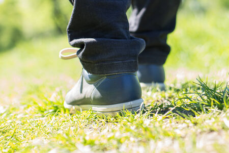 Walking outdoor. Close up image of walking feet in shoes on grassの写真素材